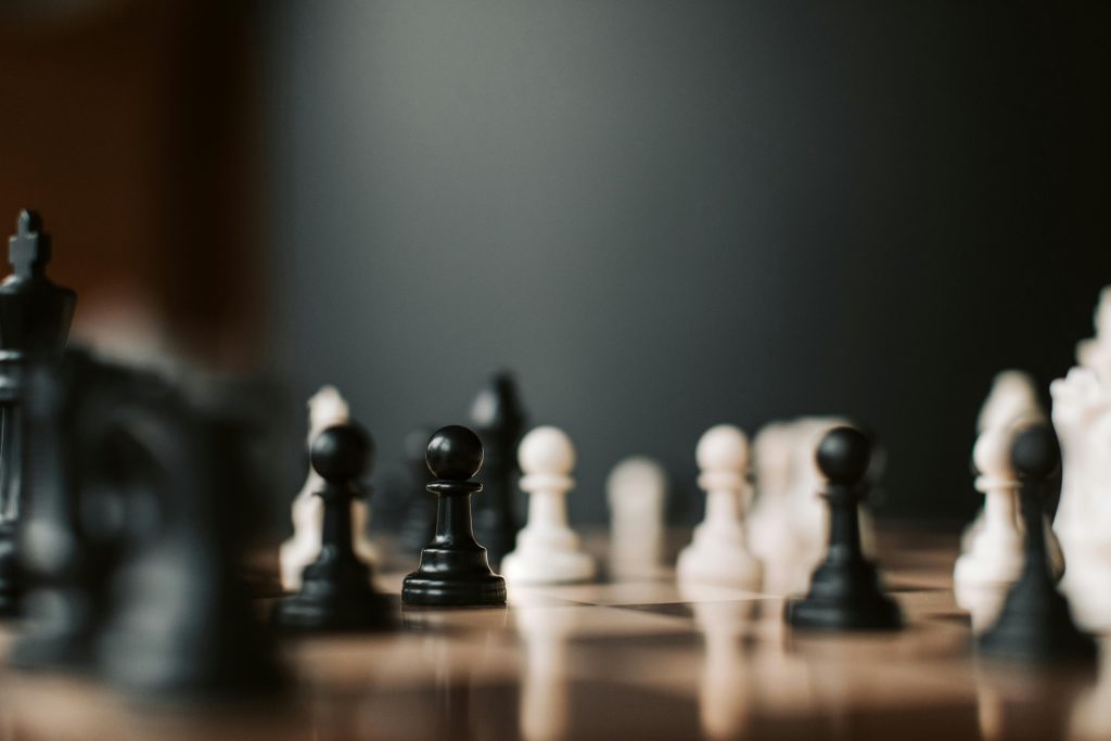 Close-up of black and white chess pieces on a chessboard, highlighting strategic gameplay.